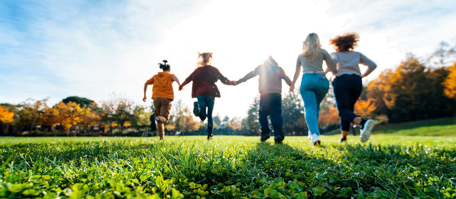 Group of multiracial people holding hands running in the park -